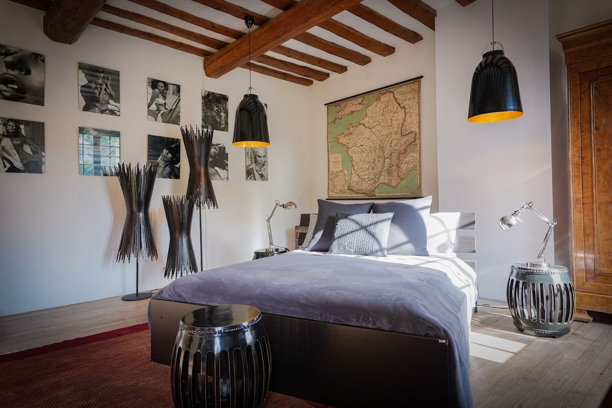 A bedroom at Mas Bleu with exposed beams and a stone wall